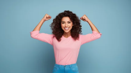 Foto op Canvas strong woman dressed in pink smiling on a light blue background showing her muscles  © Favio
