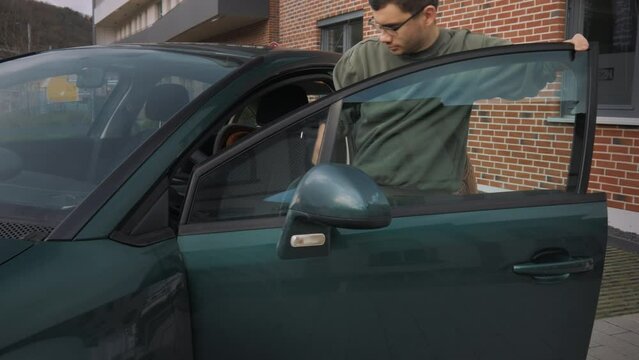 A disabled man gets into a car near the office. He opens and closes the car door.