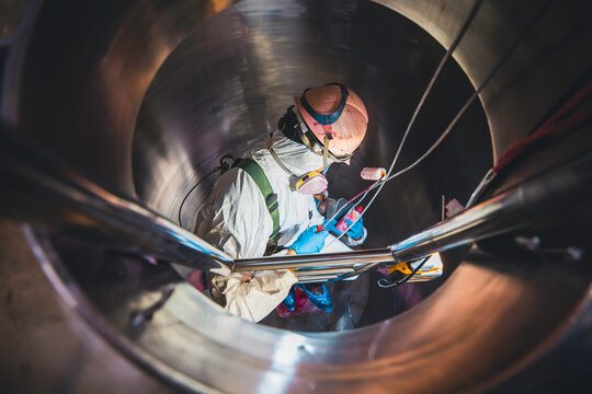 Top view male climbs up the stairs into the tank stainless chemical area confined space