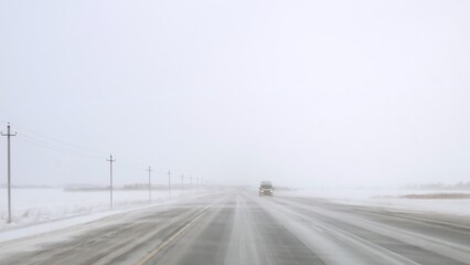 Dangerous road with ice and blizzard, view from car on icy highway. Treacherous journey through icy...