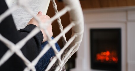 Serene man engrossed in book by warm fireplace, epitomized solitude. Scene captures essence of...