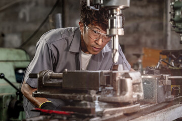 Engineer worker in production plant drilling at machine. Professional worker near drilling machine on factory. man inspecting and repairing machine for operation in workshop.