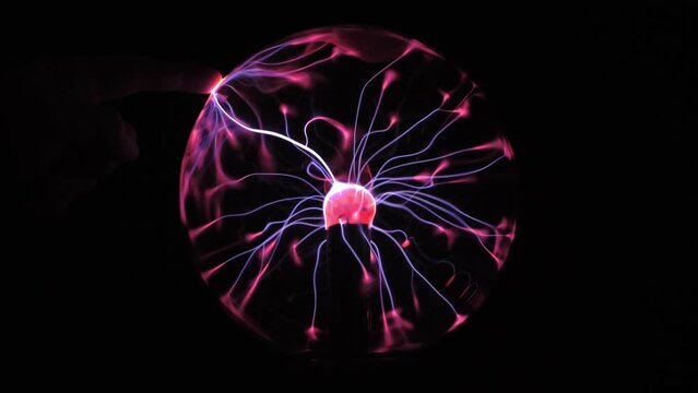 Electric Elegance: Plasma Ball Illuminated by Stormy Lightning Effects. Human fingers on it.