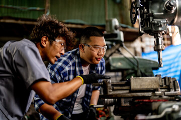 Fototapeta na wymiar Asian worker in production plant drilling at machine. Professional worker near drilling machine on factory. finishing metal working internal steel surface on lathe grinder machine with flying sparks.
