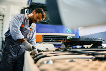 Truck mechanic inspecting vehicle in garage.