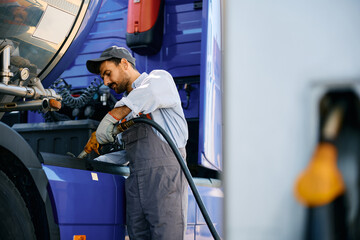 Maintenance worker filling truck fuel tank. - obrazy, fototapety, plakaty