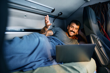 Happy driver making video call on laptop in truck cabin at night.