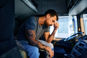 Sad professional truck driver in cabin.