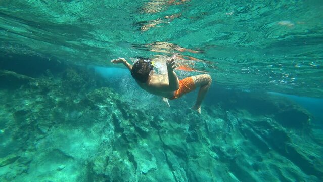 Kas, Turkey - 5th of September 2023: 4K Chubby boy tumbling backwards underwater
