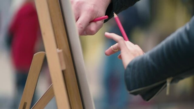 young people drawing with pencils on a malbert in the street. Close-up of hands with pencils