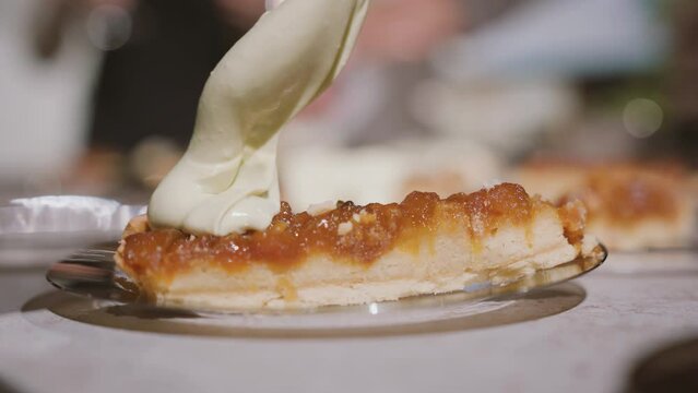 pastry chef pours a thick layer of buttercream over a slice of cake