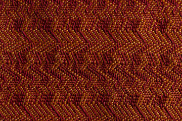 close up macro detail shot of woven twill fabric in deep red and orange, showing steeped, flattened and even twills