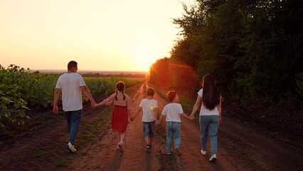 Dad mom daughter son go hand in hand outdoors in summer. Big family, group of people in nature....