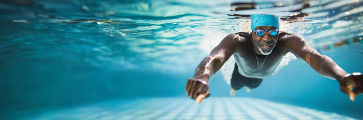 Underwater photo of a man swimming in the pool. Horizontal banner