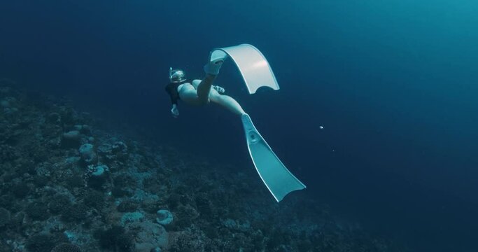 Woman freediver with fins swimming on deep ocean. Freediving in clear blue ocean