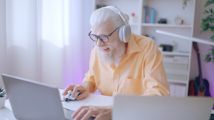 An excited senior man enjoys playing a video game with friends online, immersing himself in the...