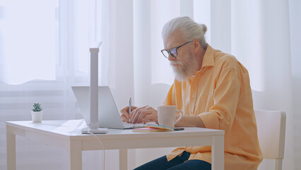 A contemporary senior man works from home, living the freelancer lifestyle in a cozy workspace