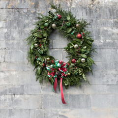 close up of a large christmas wreath with baubles ribbon pine cones laurel leaves and fir
