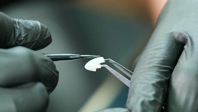 Close-up of a dentist applying paint to a veneer.