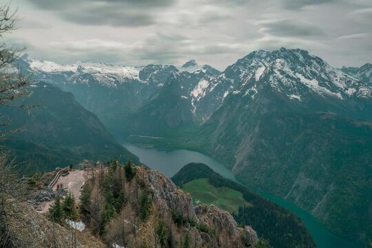 Timlapse of viewpoint of Jenner with moving tourists at lake K&ouml;nigssee at Berchtesgaden Bavaria, mountain scenery in the background with snow-capped mountains, clouds moving in the sky.
