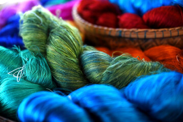Tie of colorful and shiny beautiful silk yarn dyed placed in a pile of round bamboo baskets....