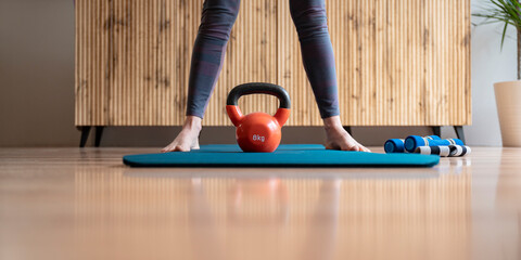 An 8 kilogram kettlebell weight placed between female feet standing on an exercise mat