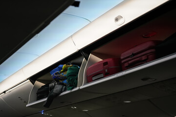 Airplane overhead locker with baggage suitcases, closeup detail