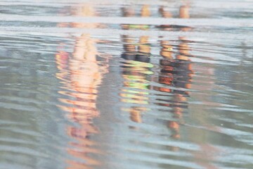 Three women walking on the beach breaking waves water, light reflections