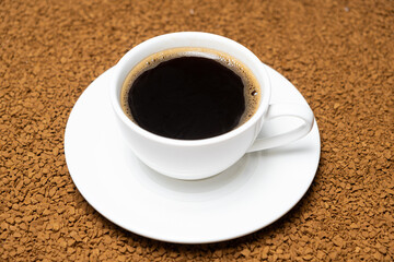 A cup of hot instant coffee on a background of freeze-dried granules