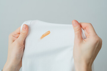 Cosmetic stains on the white clothes. The housewife evaluates the stain before removal. Liquid...