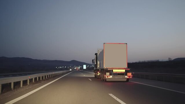 Truck with container rides on the highway road at sunrise, twilight. Transportation, industrial concept