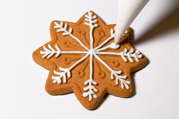 Snowflake-shaped cookies are decorated and covered with liquid white sugar icing. Gingerbread cookies close up