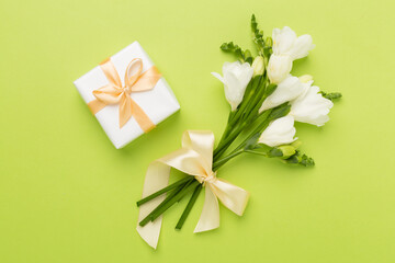 Gift box with fresia flower color background, top view