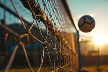 A vibrant football ball soars through the clear blue sky, surrounded by a protective fence and net, basking in the warm rays of the sun