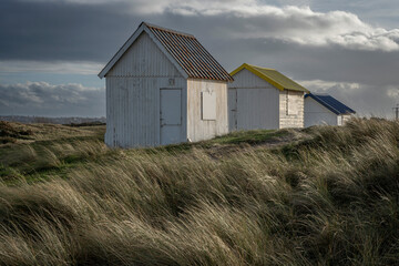 Fototapeta na wymiar Gouville, France - 12 30 2023: View of colorful bathing wooden cabins of Gouville on the dunes.