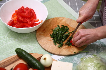Woman cutting fresh arugula in kitchen