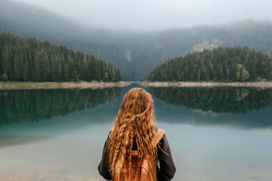 Woman Standing Alone on Shore of Mountain Lake