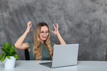 Portrait of Playful Girl in Glasses Making Faces in Front of Laptop Next to Green Flower