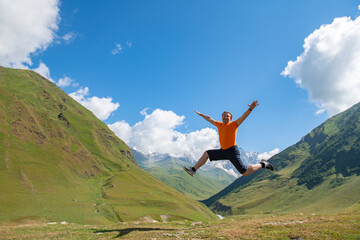 Dynamic Escape: Man in Orange T-Shirt Leaps Over Scenic Mountains