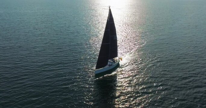 Sailing yacht with blue sails in wind waves Lonely sail boat race at sun shine. Serene water scape and transportation