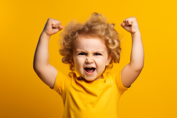 Young Child Raising Fist in Strength and Confidence yellow background - obrazy, fototapety, plakaty