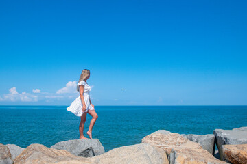 Seaside Chic: A Girl in a White Dress by the Serene Blue Sea