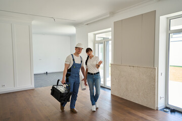 Woman showing new townhouse for male worker before repair
