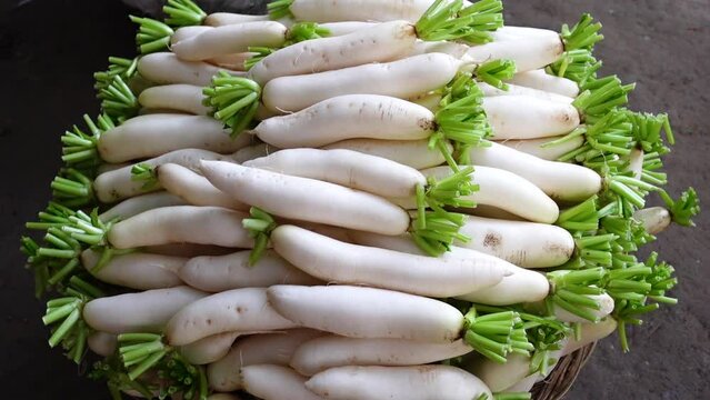 Organic long white radishes arranged in bamboo baskets are kept for sale.