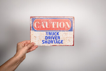 Truck Driver Shortage. Metal warning sign in a woman's hand on a white background