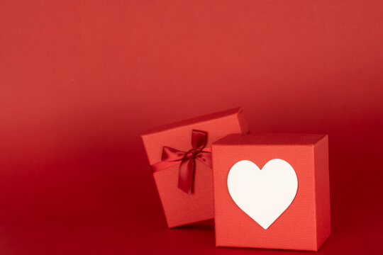 one gift box with a white hearth on the front , with space to add text or other images on an endless red background useful in advertisement. Mockup for valentine's day.