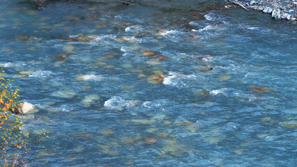 The water surface of a mountain river with a rocky bottom and splashes of water. Natural background.