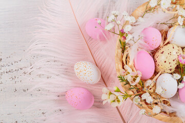 Easter candy chocolate eggs and almond sweets lying in a bird's nest decorated with flowers and...