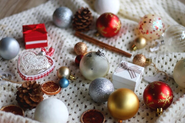 Various colorful Christmas ornaments, small presents and seasonal spices on white knitted blanket. Selective focus.