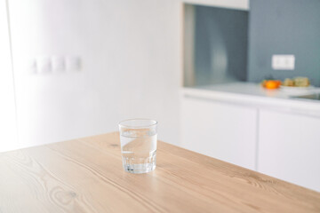 Glass of fresh cold water on table in kitchen. Space for text